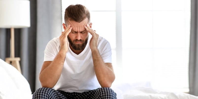 Sick man sitting on his bed