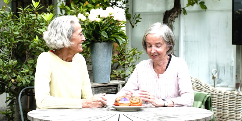 Two elderly women enjoying themselves having coffee at a cafe