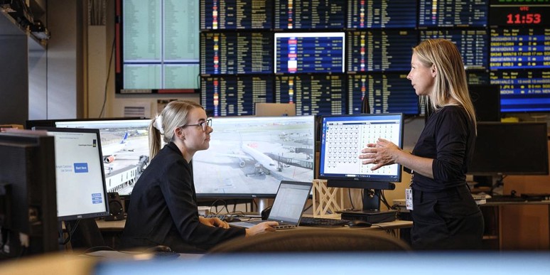 Flygplatsmedarbetare framför avgångstavlor
