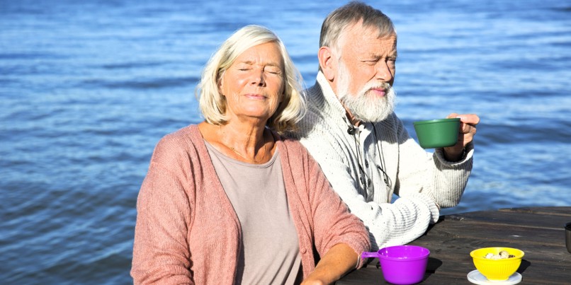 An elderly couple having coffee by the sea