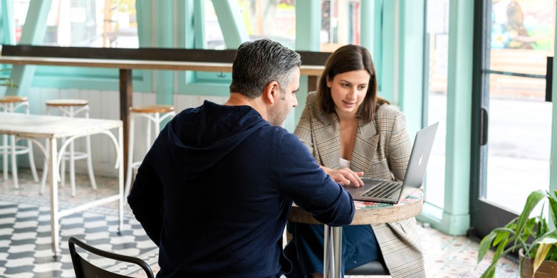 Woman and man working at a computer in a cafe