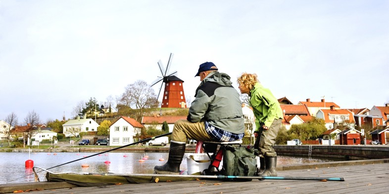 Elderly man fishing with his grandchild
